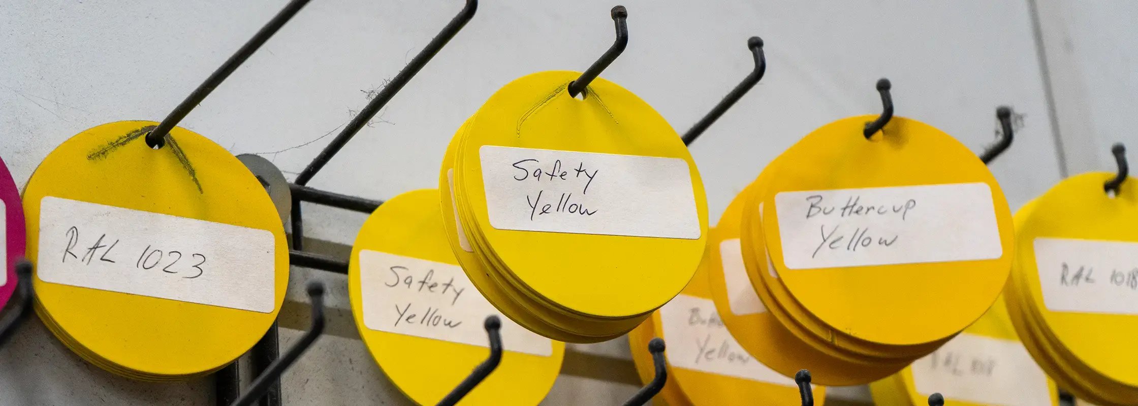 various yellow powder coating color cards hanging on a rack