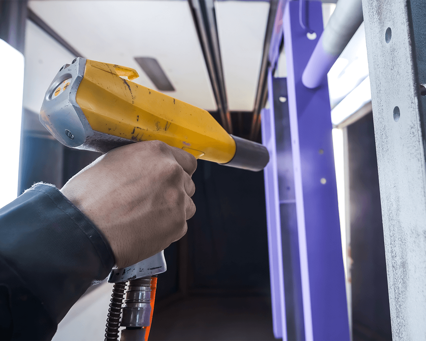 Man powder coating a piece of stainless steel 